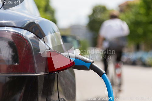 Image of Power supply plugged into an electric car being charged.