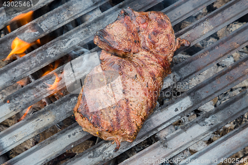 Image of Beef steaks on grill with flames.