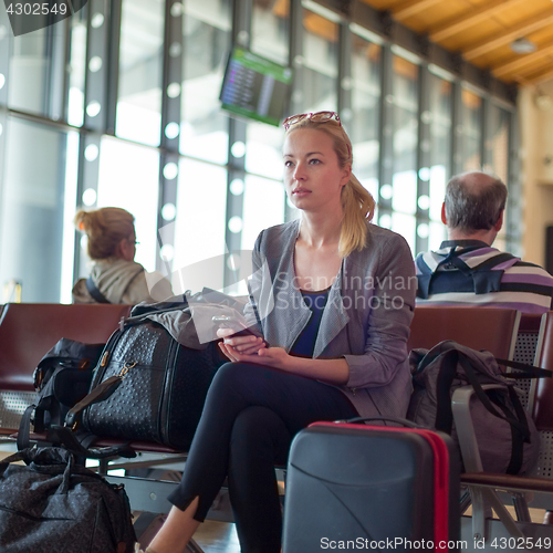 Image of Female traveler using cell phone while waiting on airport.