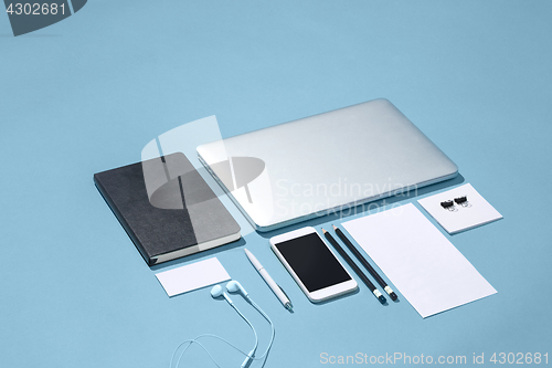 Image of The laptop, pens, phone, note with blank screen on table