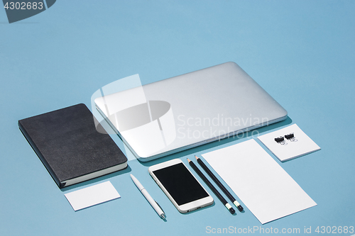 Image of The laptop, pens, phone, note with blank screen on table