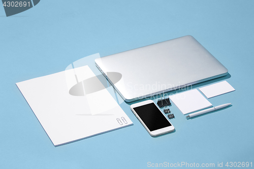 Image of The laptop, pens, phone, note with blank screen on table