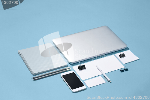 Image of The laptop, pens, phone, note with blank screen on table