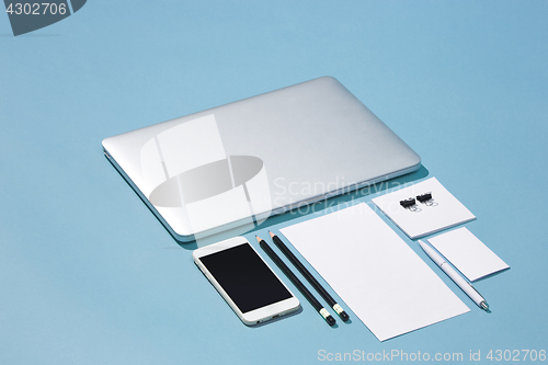 Image of The laptop, pens, phone, note with blank screen on table