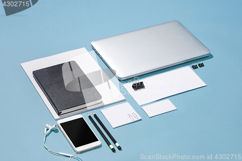 Image of The laptop, pens, phone, note with blank screen on table