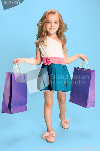 Image of The cute little caucasian brunette girl in dress holding shopping bags