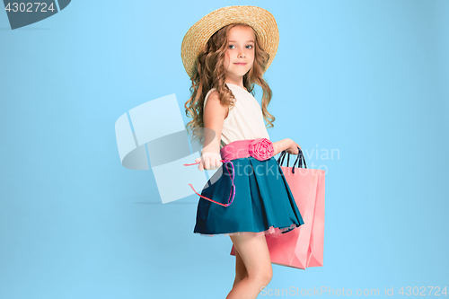 Image of The cute little caucasian brunette girl in dress holding shopping bags