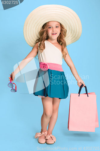 Image of The cute little caucasian brunette girl in dress holding shopping bags