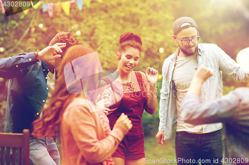 Image of happy friends dancing at summer party in garden