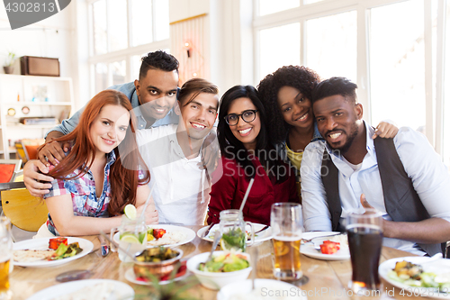 Image of happy friends eating at restaurant