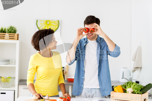 Image of happy couple cooking food and having fun at home