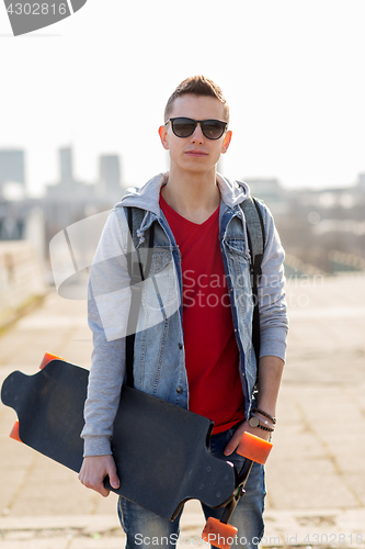 Image of happy young man or teenage boy with longboard