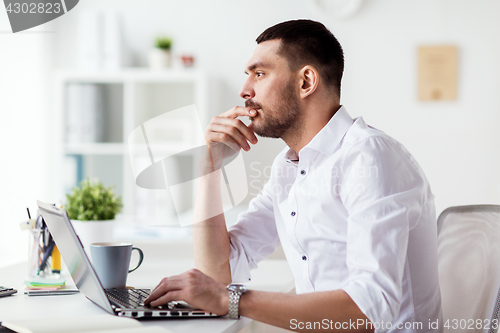 Image of businessman with laptop thinking at office