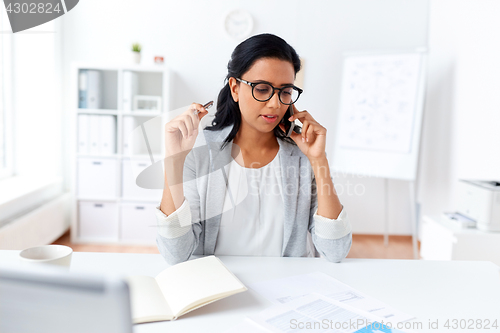 Image of businesswoman calling on smartphone at office
