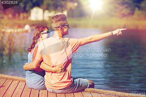 Image of happy couple pointing finger on summer river berth