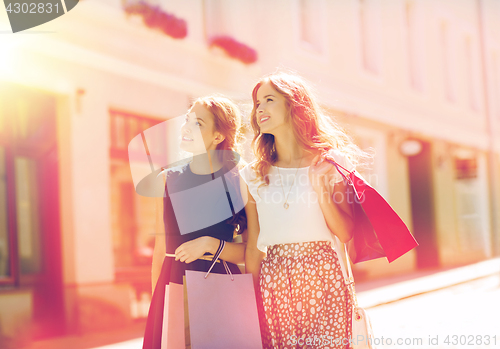 Image of happy women with shopping bags walking in city 