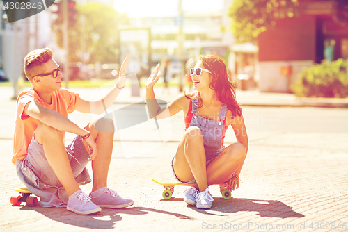 Image of teenage couple with skateboards on city street