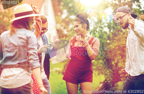 Image of happy friends dancing at summer party in garden