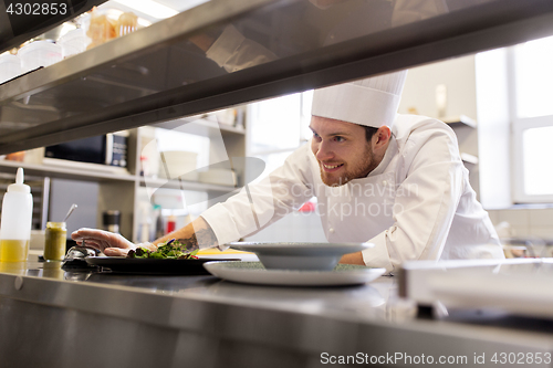 Image of happy male chef cooking food at restaurant kitchen