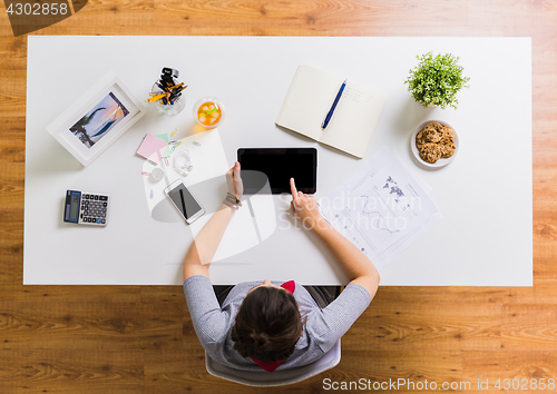 Image of woman with tablet pc and notebook at office table