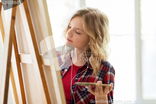 Image of student girl with easel painting at art school