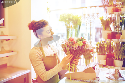 Image of smiling florist woman making bunch at flower shop