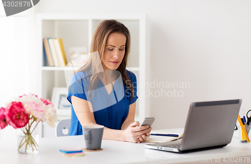 Image of woman with smartphone and laptop at office