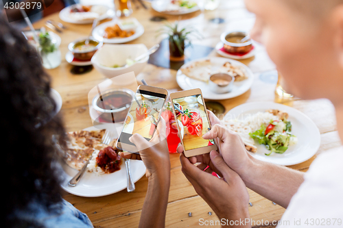 Image of couple picturing drinks by smartphones at bar