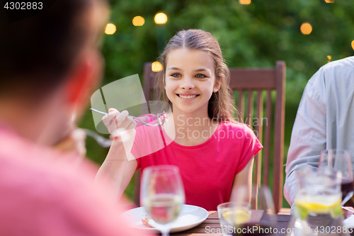 Image of happy girl eating with family at summer garden