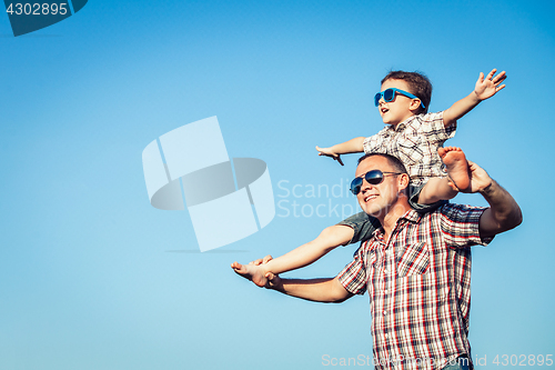 Image of Dad and son in sunglasses playing in the park at the day time.