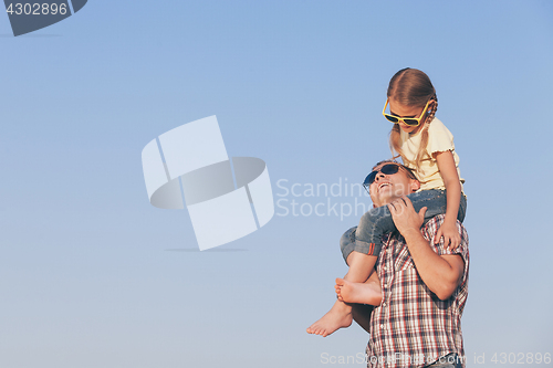 Image of Dad and daughter in sunglasses playing in the park at the day ti