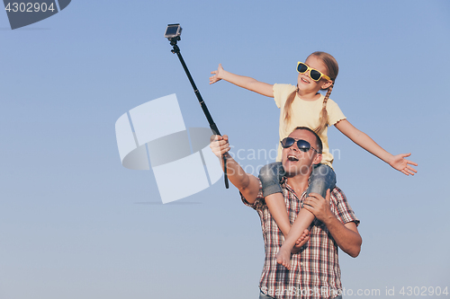 Image of Dad and daughter in sunglasses playing in the park at the day ti