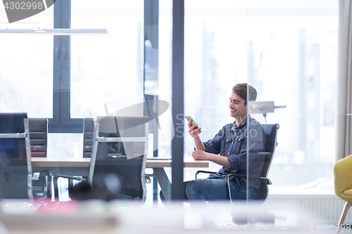 Image of Young casual businessman using smartphone