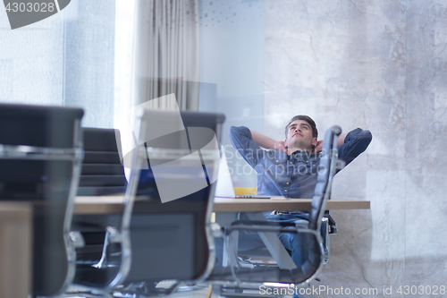 Image of young businessman relaxing at the desk