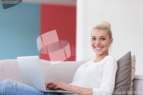 Image of Young woman using laptop at home
