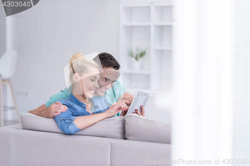 Image of couple relaxing at  home with tablet computers