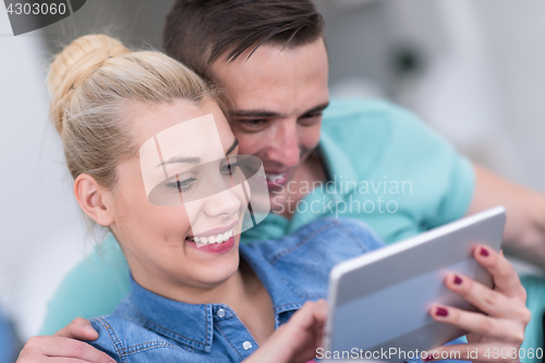 Image of couple relaxing at  home with tablet computers