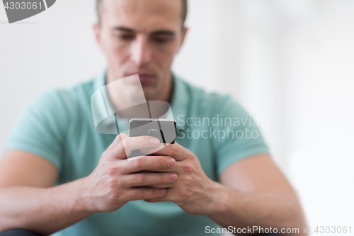 Image of young man using a mobile phone  at home