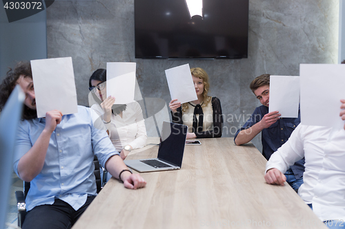 Image of startup business team holding a white paper over face