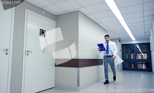 Image of doctor with clipboard walking along hospital