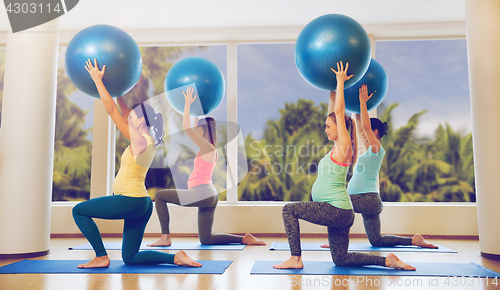 Image of happy pregnant women exercising with ball in gym