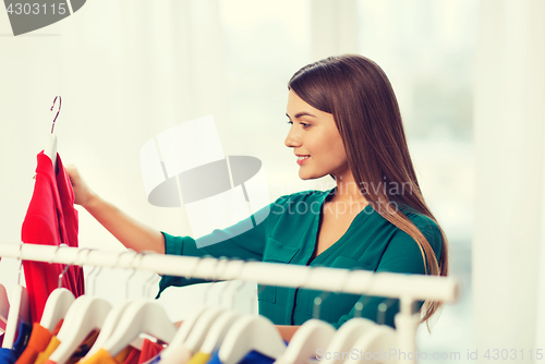 Image of happy woman choosing clothes at home wardrobe