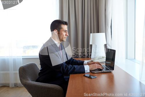 Image of businessman typing on laptop at hotel room