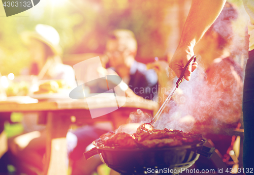 Image of man cooking meat on barbecue grill at summer party