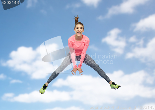 Image of happy smiling sporty young woman jumping in sky