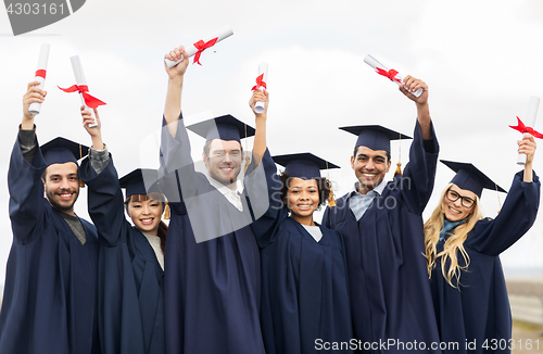 Image of happy students in mortar boards with diplomas