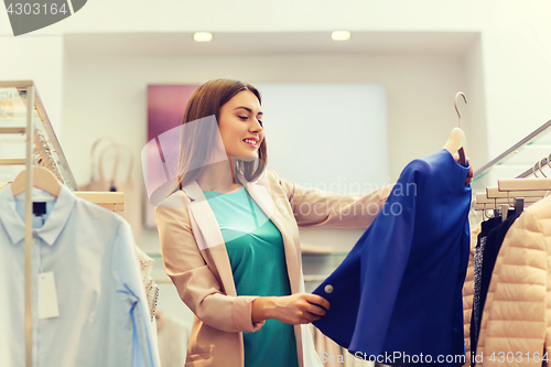 Image of happy young woman choosing clothes in mall