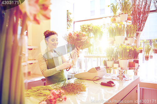 Image of smiling florist woman making bunch at flower shop