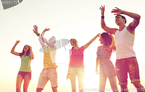 Image of smiling friends dancing on summer beach