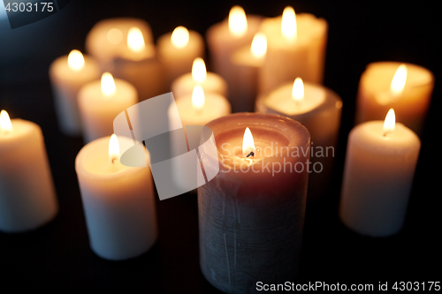 Image of candles burning in darkness over black background